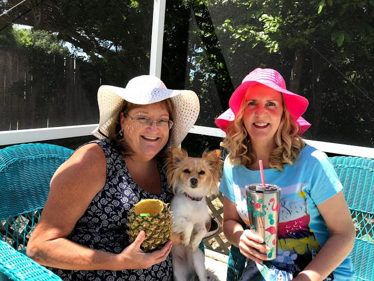 Two ladies wearing sun hats with dog